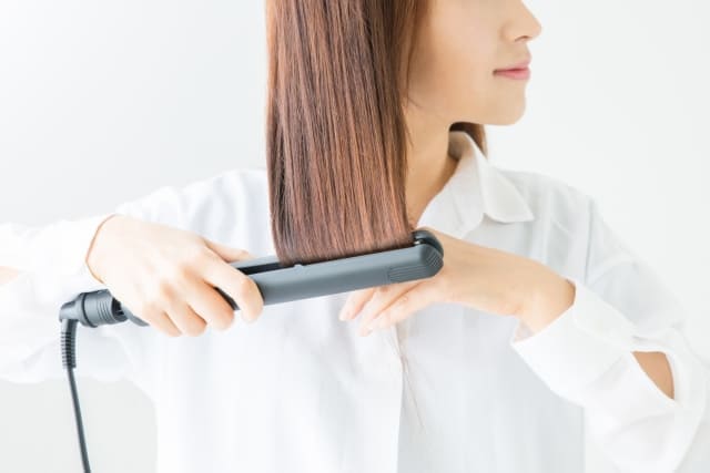 ヘアアイロンを使用している女性
