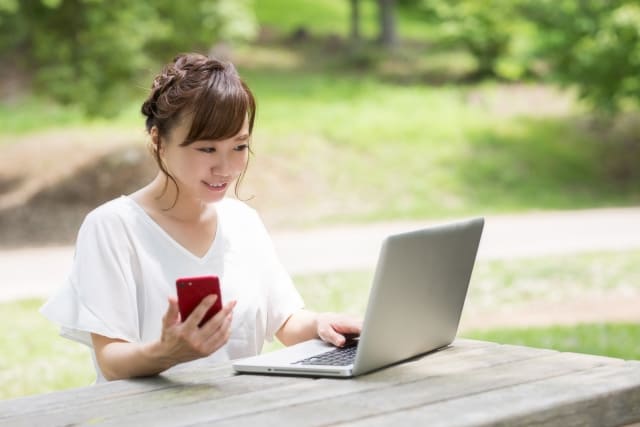 パソコンとスマホを使用している女性