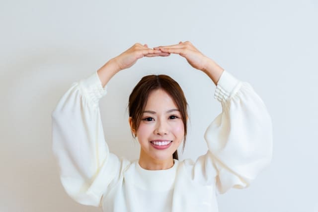 両腕で丸を作る女性