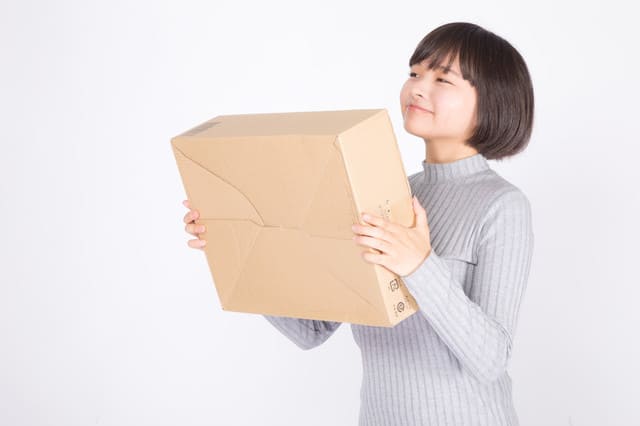 段ボールを手に持つ女性